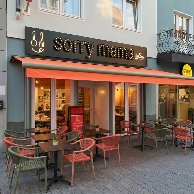 Außenansicht von Sorry Mama in der Kölner Innenstadt mit Terrasse und orangefarbener Markise